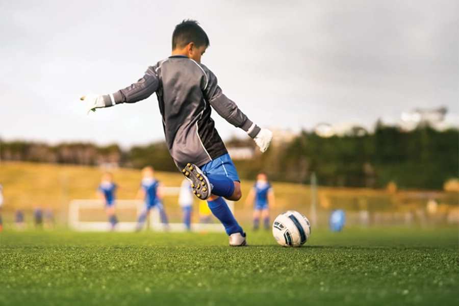 Kid kicking soccer ball toward goal