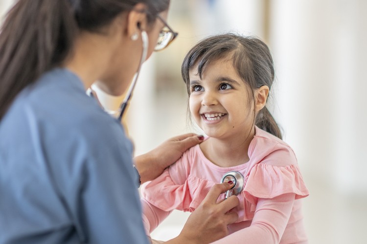 Medical professional listening to pediatric girl's heartbeat